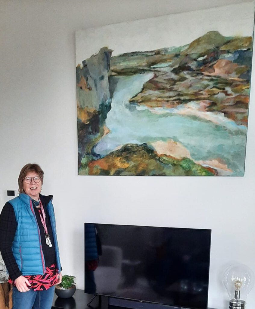 Jacqueline staat naast een groot schilderij in een woonkamer